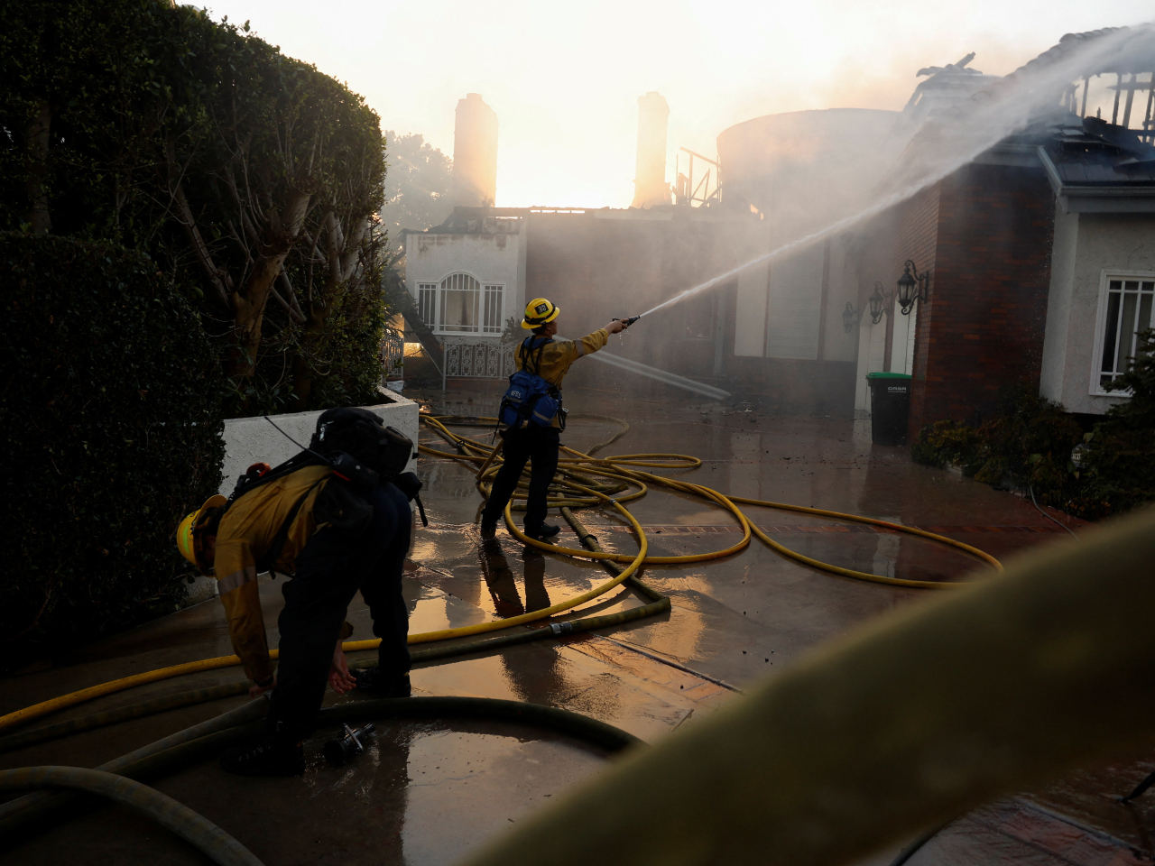 Firefighters use a water hose to battle the Norte Fire as wildfires rage in San Clemente, California. Photo: Reuters