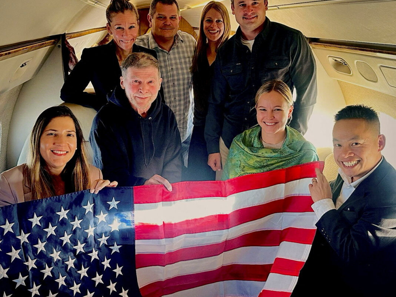 Stephen Hubbard, 74, with family members and US officials aboard a flight back home from Russia. Photo: Reuters via US Government.