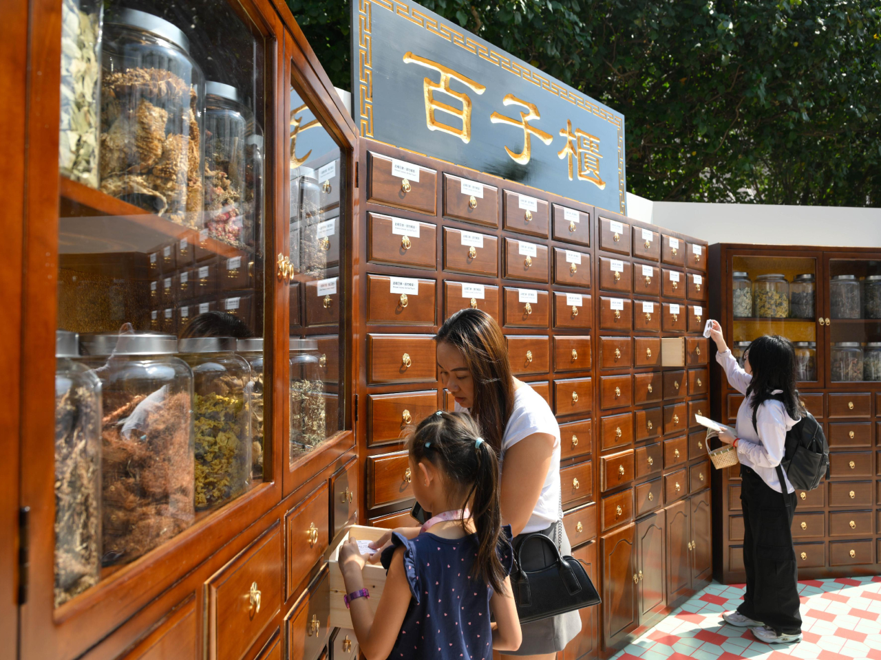 主題裝置將舊香港元素融入像素化視覺語言，例如讓參加者體驗「執藥」的傳統中藥舖「香江藥號」。（政府新聞處）